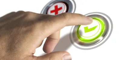 Mão humana pressionando um botão verde com símbolo de marca de verificação, ao lado de um botão vermelho com um X, representando escolha entre aprovação e rejeição.